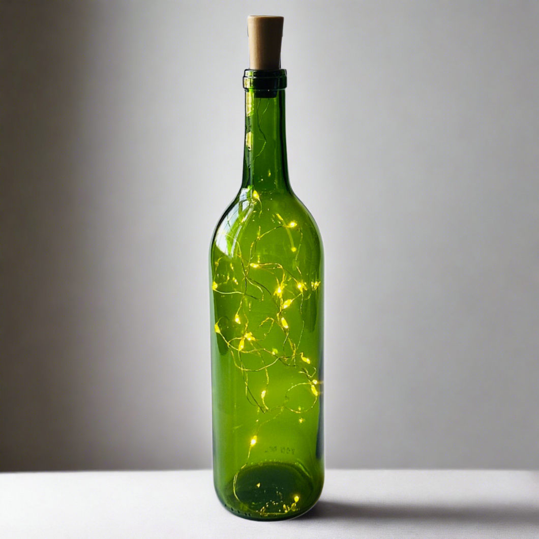 green wine bottle with white fairy lights inside