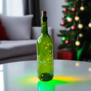 green wine bottle with colored fairy lights inside on a coffee table with a Christmas tree in the background 